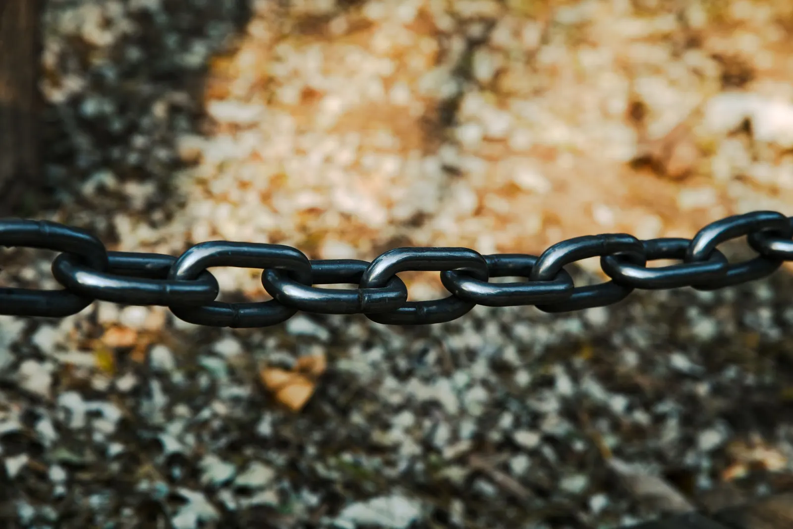 Een zwarte metalen ketting hangt horizontaal gespannen, de schakels haken in elkaar