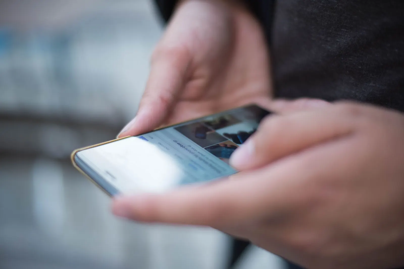 Duas mãos seguram um celular e rolam o feed de uma rede social