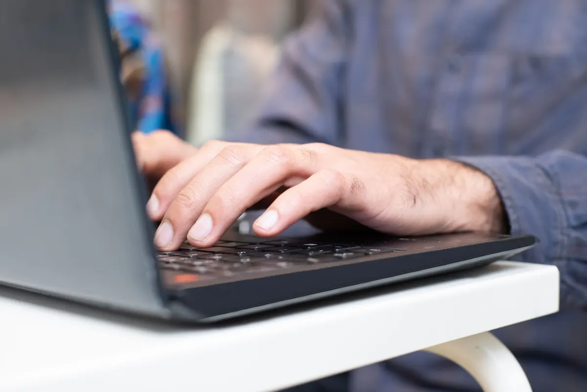 Een hand typt op het toetsenbord van een laptop