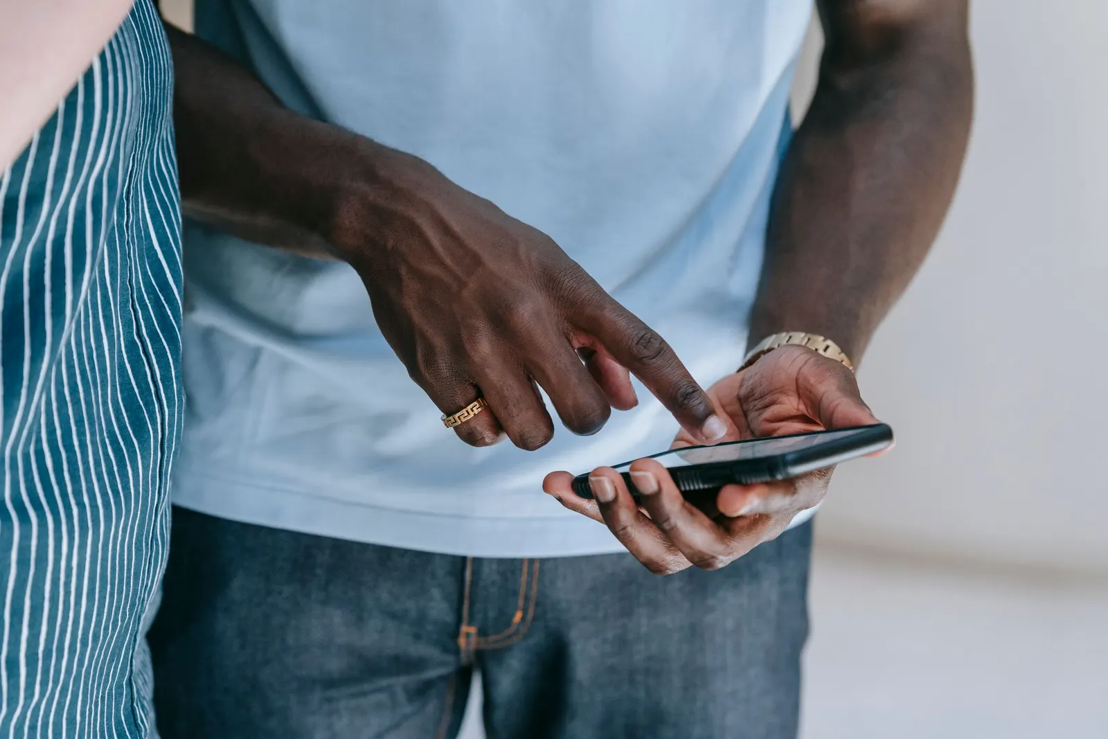 Alguém rola a tela de um smartphone com o dedo indicador, segurando o aparelho na outra mão