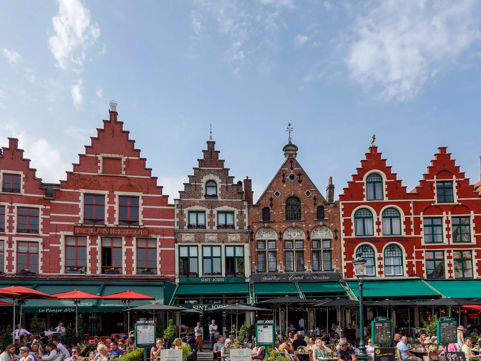 De kleurrijke trapgevels aan de Markt in Brugge, met terrassen en winkels op de benedenverdieping