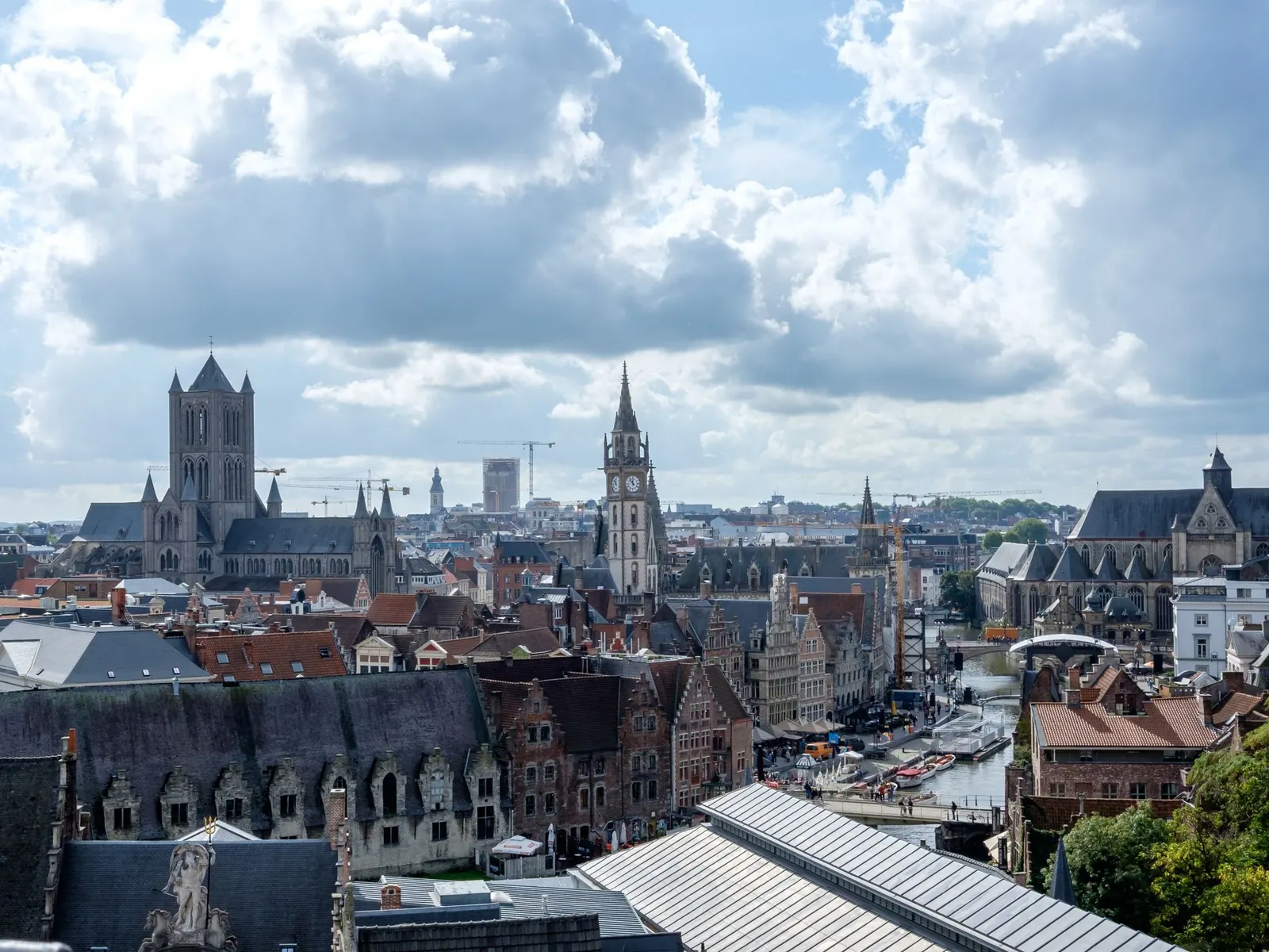 Zicht over de daken van Gent met de torens van de binnenstad onder een wolkenlucht